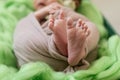 Feet of a newborn baby, toes  of a child, the first days of life after birth, green background, funny spread fingers Royalty Free Stock Photo