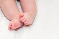 Feet newborn baby on a white bedspread. Small baby legs close up Royalty Free Stock Photo