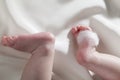 Feet of a newborn baby on white silk background and a white feather. Little baby legs Royalty Free Stock Photo