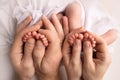 Feet of newborn twins. Parents, father mother hold newborn twins by the legs.