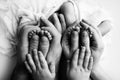 Feet of newborn twins. Parents, father mother older brother hold newborn twins