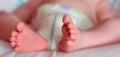 Feet of a one months old baby wearing diapers lying in bed Royalty Free Stock Photo