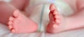 Feet of a one months old baby wearing diapers lying in bed Royalty Free Stock Photo