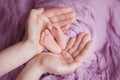 The feet in the palms, the mother holds the feet of her newborn child in her hands