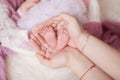 The feet in the palms, the mother holds the feet of her newborn child in her hands Royalty Free Stock Photo