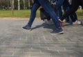 Feet of people walking in sports shoes down the street on a sunny day Royalty Free Stock Photo