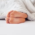 Feet, person and soles in bed with blanket for sleeping, comfort and warmth in the morning. Foot, toes and heels with