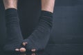 The feet of the poor debtor`s in black holey socks on a black background