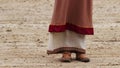 Feet of poor woman in medieval clothes begging. Pauper girl dressed in old rags