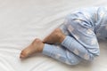 feet of preschool baby boy on blue pajama lying on white bed at home. plump legs of sleeping 3 year old caucasian child