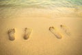 Feet prints on the sand of the beach with sea wave. Royalty Free Stock Photo