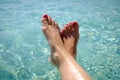 Feet with red pedicure of girl on the background of sea. Girl at the resort. Female feet on sea background. Royalty Free Stock Photo