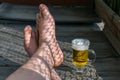 Feet of a resting man with a mug of light beer Royalty Free Stock Photo