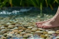 feet resting on pebbles in a shallow pool with a water stream Royalty Free Stock Photo