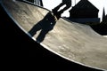 Feet of a rollerblader with inline skates riding over the halfpipe in a skate park, dramatic backlit shot with hard shadows Royalty Free Stock Photo