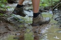 feet in rugged trail shoes stepping over a muddy brook Royalty Free Stock Photo