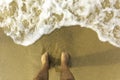 Feet in sand on sandy beach with sea foam Royalty Free Stock Photo
