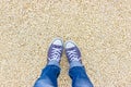 Feet selfie. Female feet in blue sneakers on a pebble beach Royalty Free Stock Photo