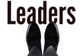 Feet with shiny shoes above written leaders-