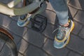 Feet shod in bright sneakers are next to the bicycle