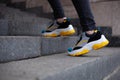 Feet shod in sneakers multi-colored yellow, white, black and blue climb the stairs