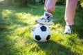 Feet in sneakers and soccer ball on grass in sun. children play football. Royalty Free Stock Photo