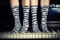 feet in socks with musical notes design on a piano keyboard Royalty Free Stock Photo