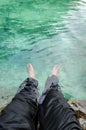 Feet submerged in tropical water of emerald pool in Krabi, Thailand. Selective focus on leg.