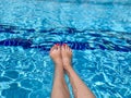 Feet in swimming pool water. Selfie of legs and barefoot with red pedicure and manicure nails on blue sea background. Vacation at Royalty Free Stock Photo