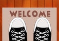 Feet teen in sneakers close up on a doorway rug that says Welcome in front of the house.