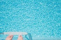 Feet about to climb down ladder into a sparkling pool Royalty Free Stock Photo