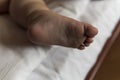 feet of toddler baby girl wearing diapers lying on white bed at home. plump legs of sleeping one year old caucasian Royalty Free Stock Photo