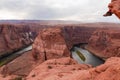 Feet of Tourist person hanging from rock cliff with scenic aerial view of Horseshoe bend on Colorado river, Page, Arizona Royalty Free Stock Photo