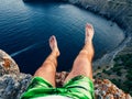 Feet tourist sitting on top of the mountain against the sea