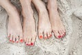 Feet of two women on a sand