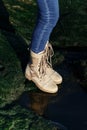 Feet in unisex jeans and khaki boots on green grass nature background