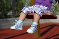 Feet of unrecognizable baby swinging on playground Royalty Free Stock Photo