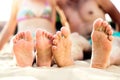 Feet of unrecognizable couple sitting on the sandy beach