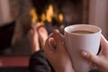 Feet warming at a fireplace with coffee