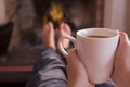 Feet warming at fireplace with coffee