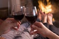 Feet warming at fireplace with hands holding wine