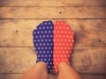 Feet wearing blue and red socks with white star shape on wooden Royalty Free Stock Photo