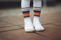 Feet wearing white sneakers and multicolored striped socks. Generate ai