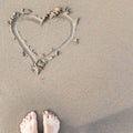 Feet on the wet sand on the beach with heart on the sand Royalty Free Stock Photo