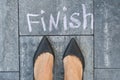 The feet of a woman in black classic shoes before the word finis