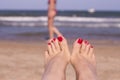 Feet of woman with nails painted red on the sand of the sea Royalty Free Stock Photo