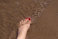 Feet of woman with nails painted red on the sand of the sea Royalty Free Stock Photo