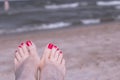 Feet of woman with nails painted red on the sand of the sea Royalty Free Stock Photo