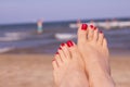 Feet of woman with nails painted red on the sand of the sea Royalty Free Stock Photo