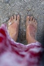 Sunburnt feet of a woman in transparent ocean water. Sand and shells.